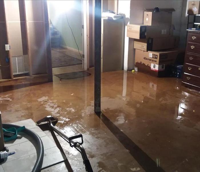 Basement with standing water around furniture and boxes