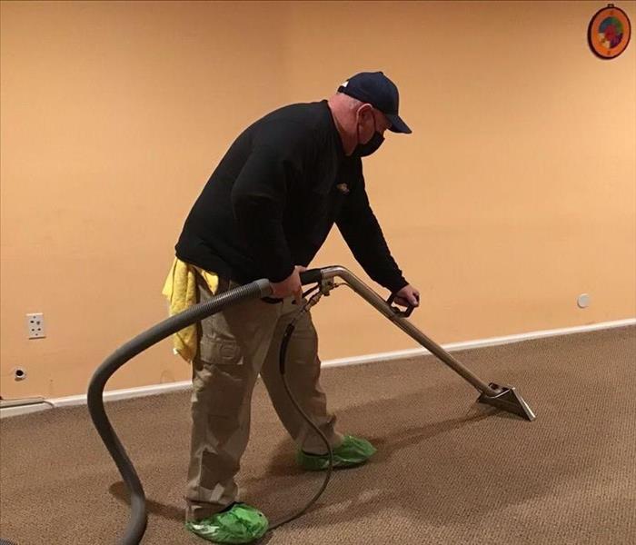 SERVPRO technicians with water extraction equipment on wet carpet