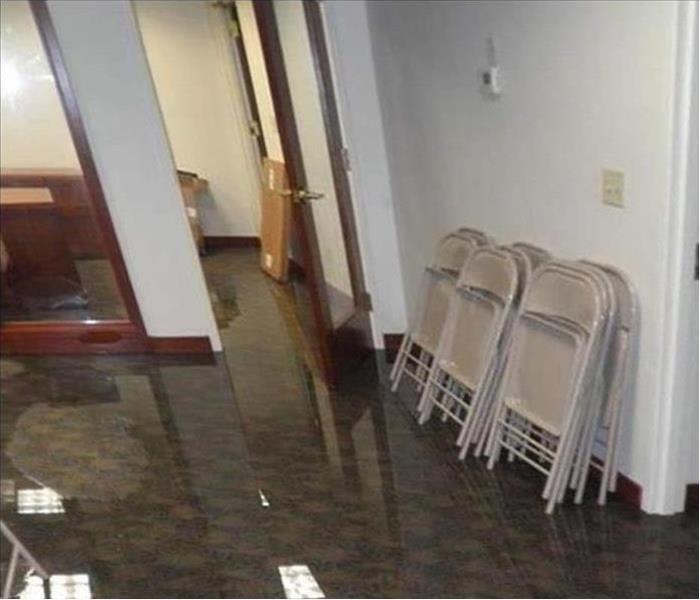 inch of water on carpeted office with folding chairs stacked against a wall