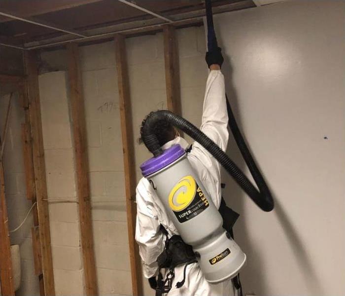 SERVPRO technician using a HEPA vacuum on a mold damaged room